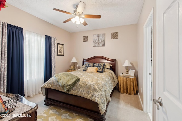 carpeted bedroom with a ceiling fan and a textured ceiling