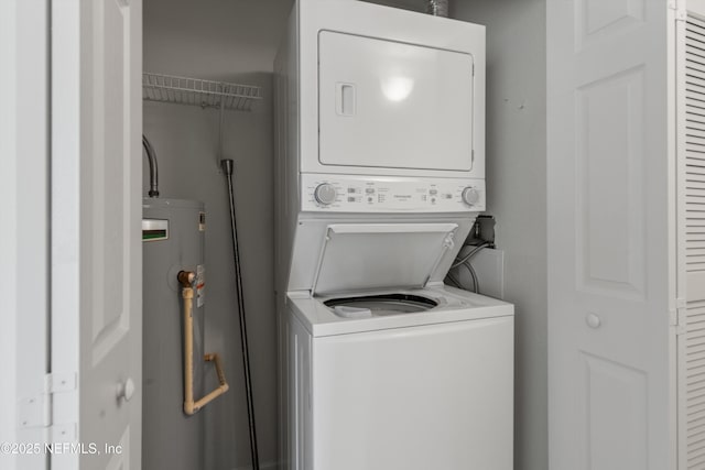 laundry area with water heater and stacked washer / dryer