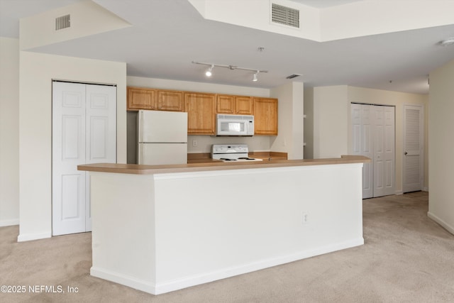 kitchen featuring a center island, light colored carpet, track lighting, and white appliances