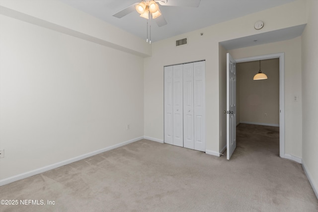 unfurnished bedroom with light colored carpet, ceiling fan, and a closet