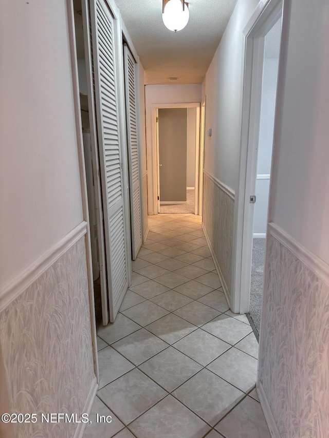 hallway featuring light tile patterned floors and a textured ceiling