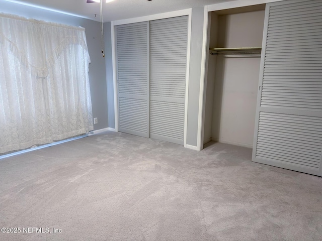 unfurnished bedroom with multiple closets and light carpet