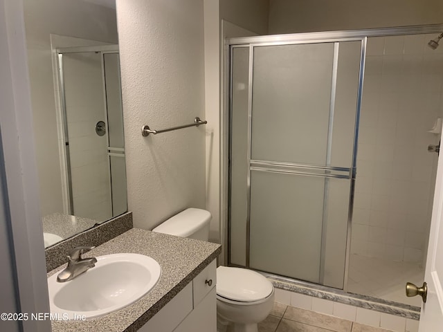 bathroom featuring tile patterned floors, vanity, toilet, and an enclosed shower