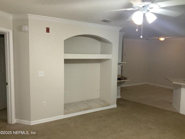 carpeted empty room with ceiling fan, crown molding, and built in shelves