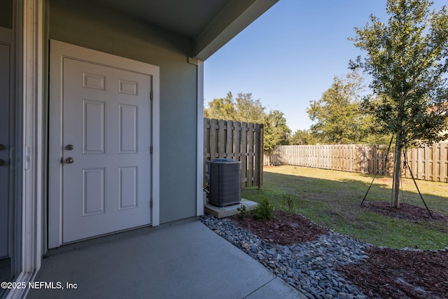 property entrance featuring a patio, a yard, and cooling unit