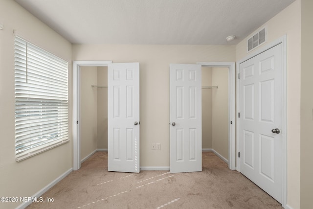 unfurnished bedroom featuring light colored carpet, a spacious closet, and a closet