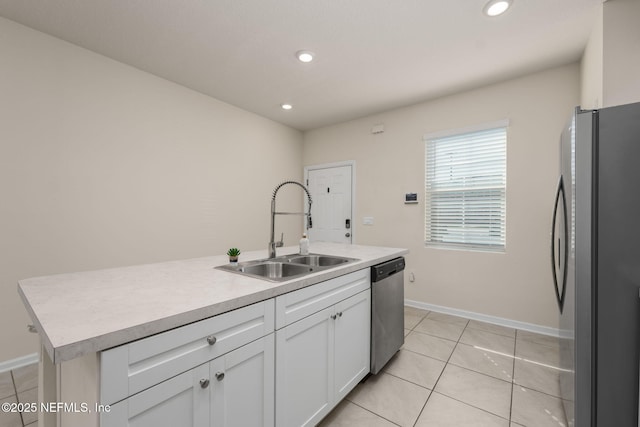 kitchen featuring sink, light tile patterned floors, stainless steel appliances, a kitchen island with sink, and white cabinets