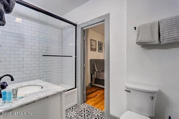 full bathroom featuring toilet, vanity, and bath / shower combo with glass door