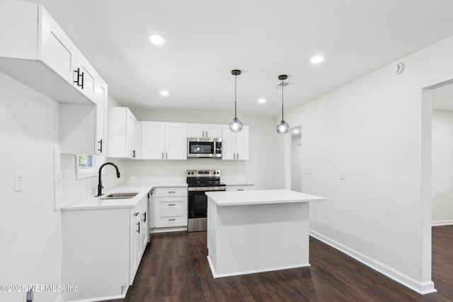 kitchen featuring sink, white cabinetry, decorative light fixtures, appliances with stainless steel finishes, and a kitchen island