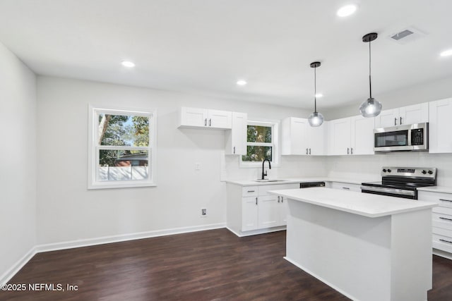 kitchen with stainless steel appliances, sink, white cabinets, and decorative light fixtures