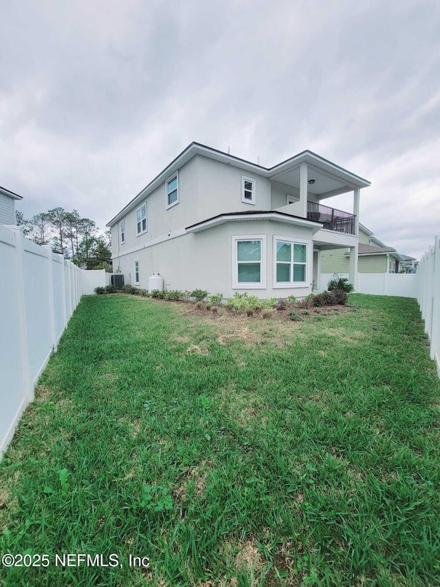 view of side of home featuring a balcony, a yard, and central air condition unit