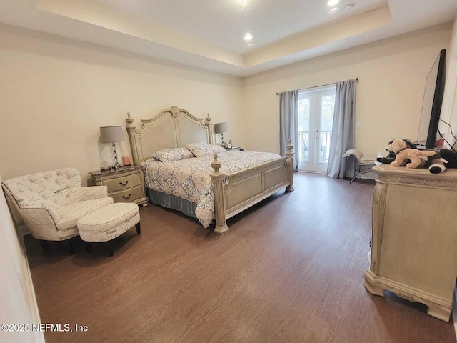 bedroom featuring a raised ceiling, access to outside, dark hardwood / wood-style flooring, and french doors