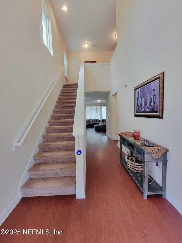 stairway with a towering ceiling and hardwood / wood-style flooring