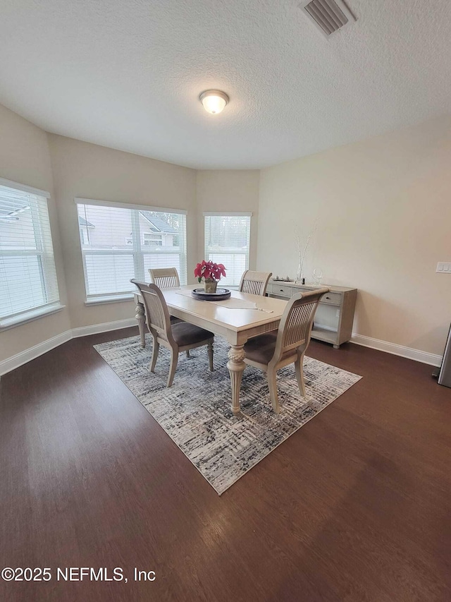 dining room featuring dark hardwood / wood-style floors, a textured ceiling, and a wealth of natural light