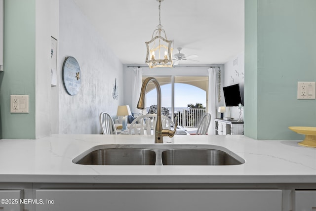 kitchen featuring an inviting chandelier, sink, decorative light fixtures, and light stone countertops