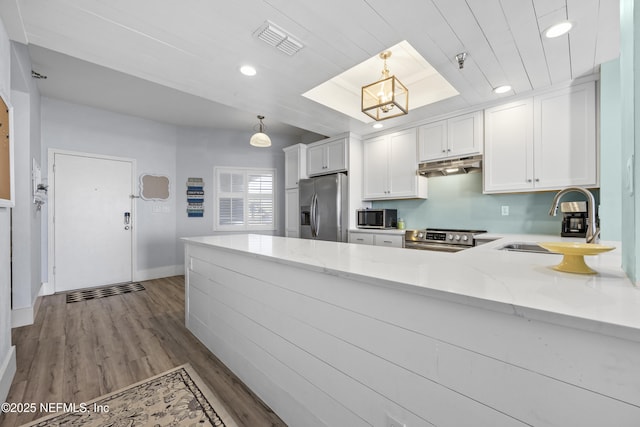 kitchen featuring appliances with stainless steel finishes, sink, hanging light fixtures, and white cabinets