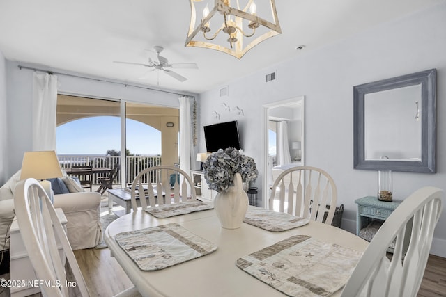 dining space featuring ceiling fan with notable chandelier and dark hardwood / wood-style floors