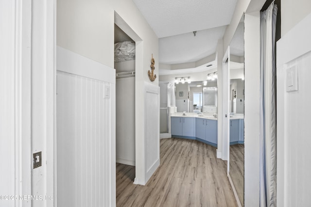 hallway featuring sink, a textured ceiling, and light wood-type flooring