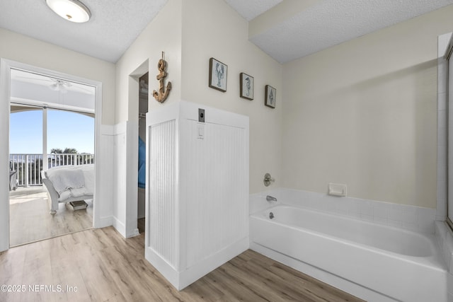 bathroom with a bathtub, wood-type flooring, and a textured ceiling