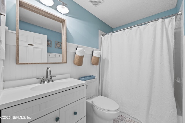 bathroom featuring vanity, curtained shower, a textured ceiling, and toilet