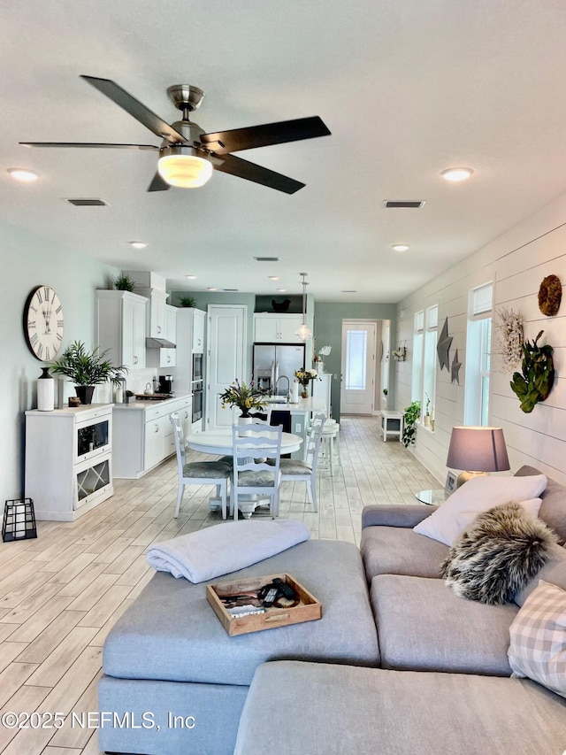 living room featuring ceiling fan and wood walls