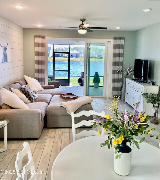 living room featuring ceiling fan and wood walls