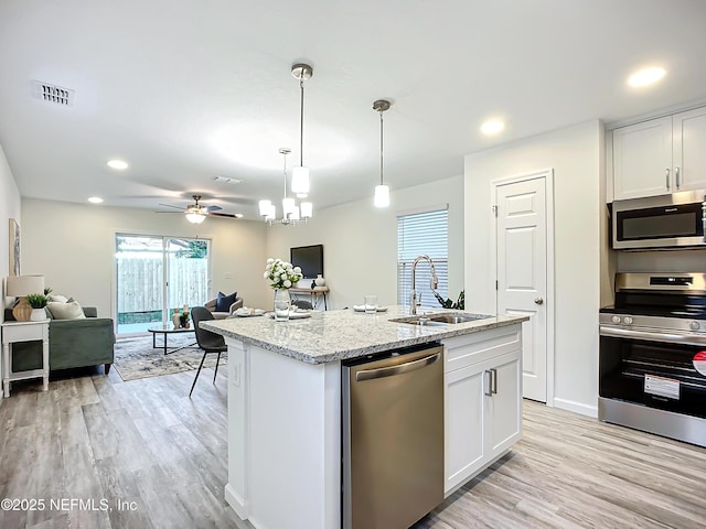 kitchen featuring sink, appliances with stainless steel finishes, white cabinetry, light hardwood / wood-style floors, and an island with sink