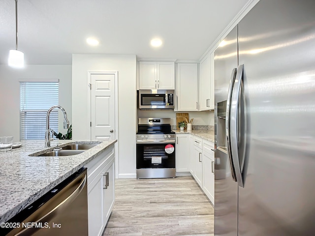 kitchen with white cabinetry, stainless steel appliances, sink, and hanging light fixtures