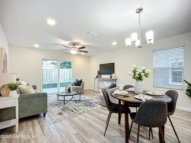 dining room with ceiling fan with notable chandelier and light hardwood / wood-style flooring