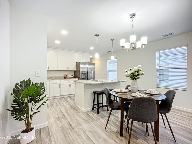 dining area featuring a notable chandelier and light wood-type flooring