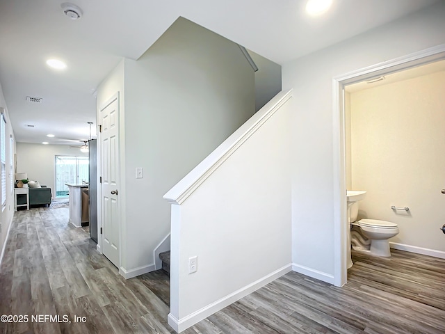 stairs with wood-type flooring and ceiling fan