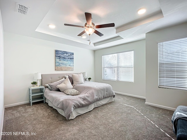 bedroom featuring ceiling fan, a tray ceiling, and carpet floors