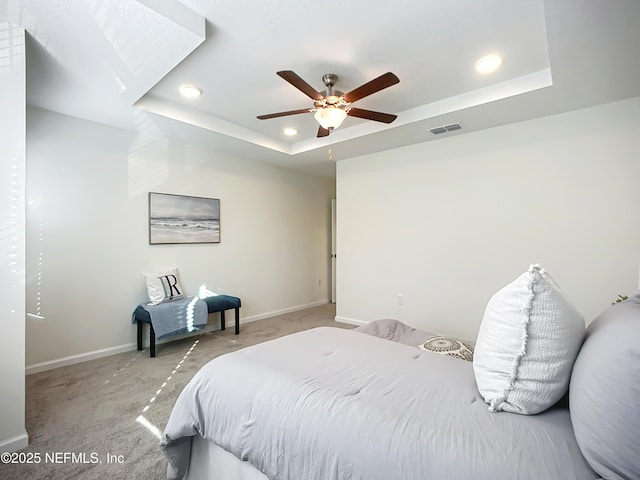 carpeted bedroom featuring ceiling fan and a raised ceiling