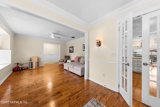 living area with hardwood / wood-style flooring, ornamental molding, and a textured ceiling