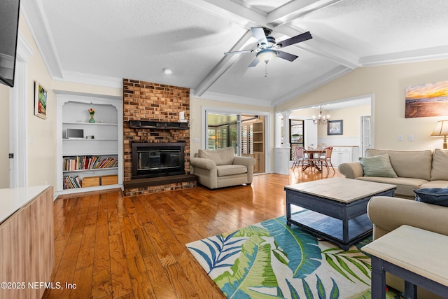 living room featuring built in features, wood-type flooring, lofted ceiling with beams, a textured ceiling, and a brick fireplace