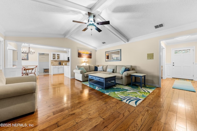 living room with lofted ceiling with beams, ornamental molding, a textured ceiling, and light hardwood / wood-style flooring