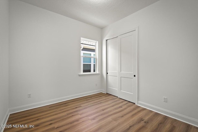 empty room with wood-type flooring and a textured ceiling