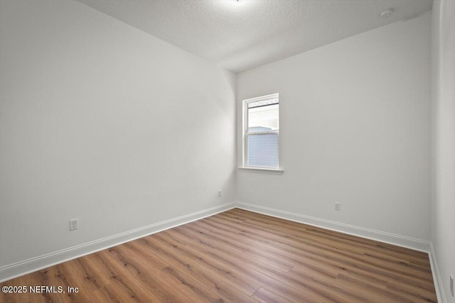 unfurnished room with hardwood / wood-style flooring and a textured ceiling