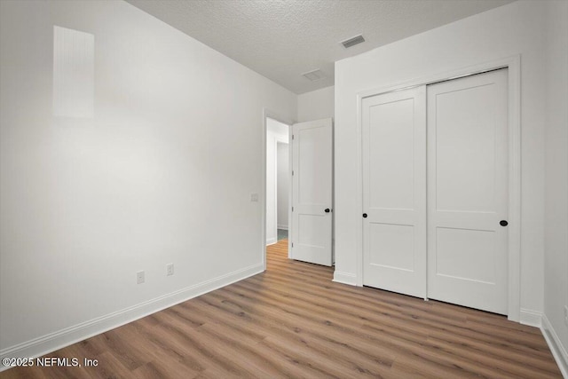 unfurnished bedroom with hardwood / wood-style flooring, a textured ceiling, and a closet