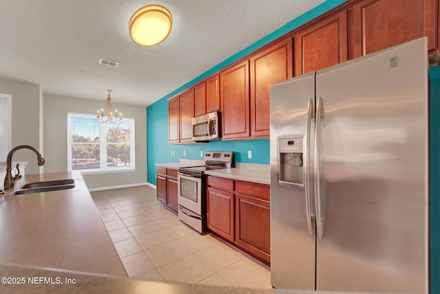 kitchen featuring sink, decorative light fixtures, a chandelier, light tile patterned floors, and stainless steel appliances