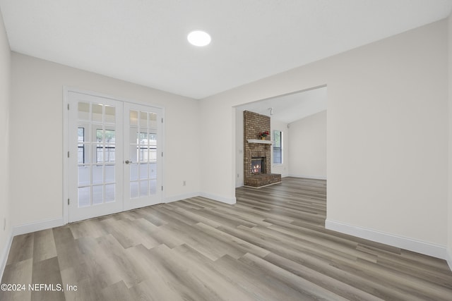 unfurnished living room with french doors, a fireplace, and light wood-type flooring