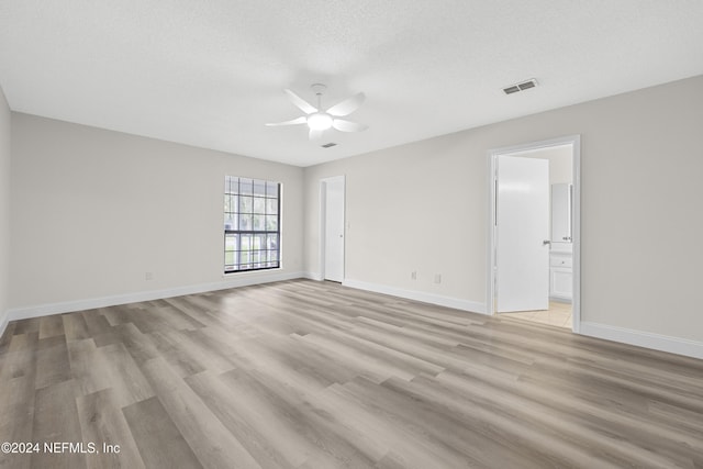 empty room with ceiling fan, a textured ceiling, and light wood-type flooring