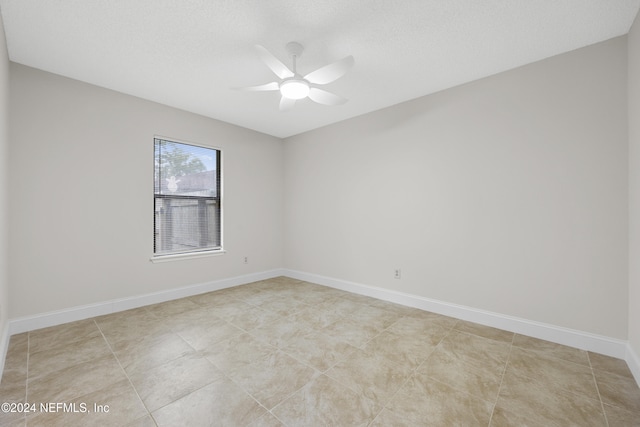 empty room with a textured ceiling, ceiling fan, and light tile patterned flooring