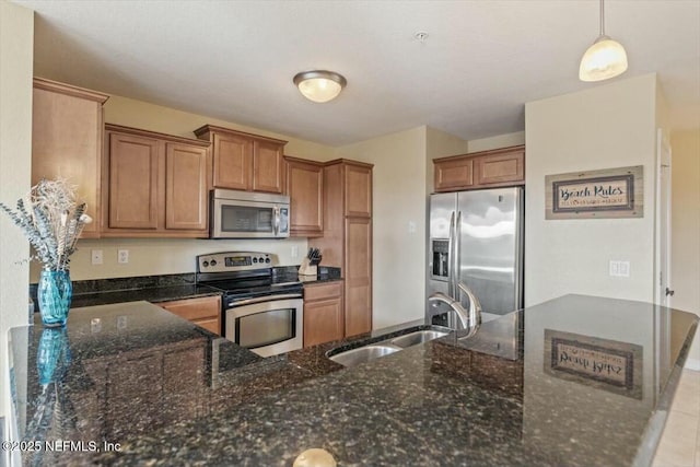 kitchen featuring light tile patterned flooring, sink, hanging light fixtures, appliances with stainless steel finishes, and dark stone counters