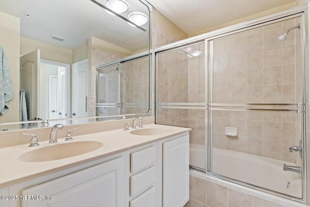 bathroom with vanity, shower / bath combination with glass door, and a textured ceiling