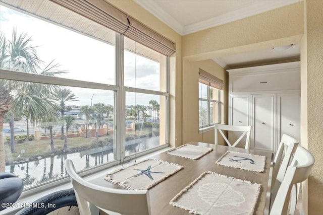 dining space with a water view and crown molding