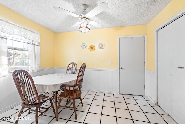 dining room featuring ceiling fan, light tile patterned floors, and a textured ceiling