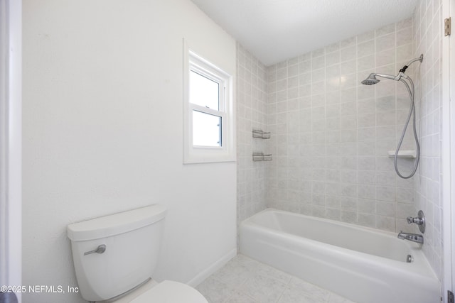 bathroom with tile patterned flooring, tiled shower / bath, and toilet