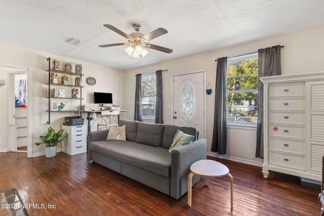 living room with ceiling fan, a textured ceiling, dark hardwood / wood-style floors, and a healthy amount of sunlight