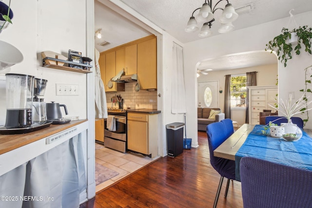 kitchen with hardwood / wood-style flooring, electric range, decorative backsplash, a textured ceiling, and ceiling fan with notable chandelier